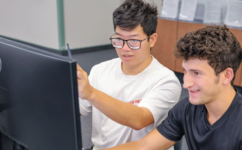 Two male students looking at a monitor.